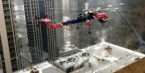 Helicopter delivering chiller equipment to a rooftop in downtown Chicago.