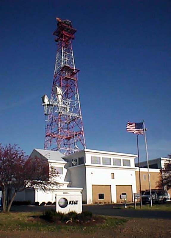 Small building with tall communications tower behind it.