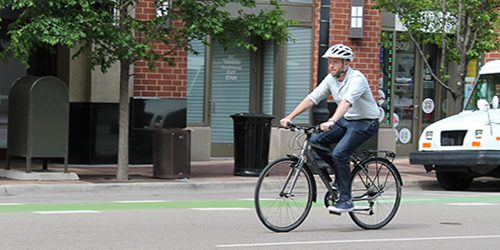 A staff member rides a shared GBA bike down the street.