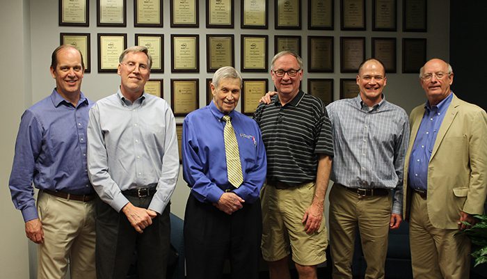 Firm founders Bob Bayne, Dan Doyle, Dave Grumman, Al Butkus, Chad Luning, and Jeff Conner in front of a wall of awards