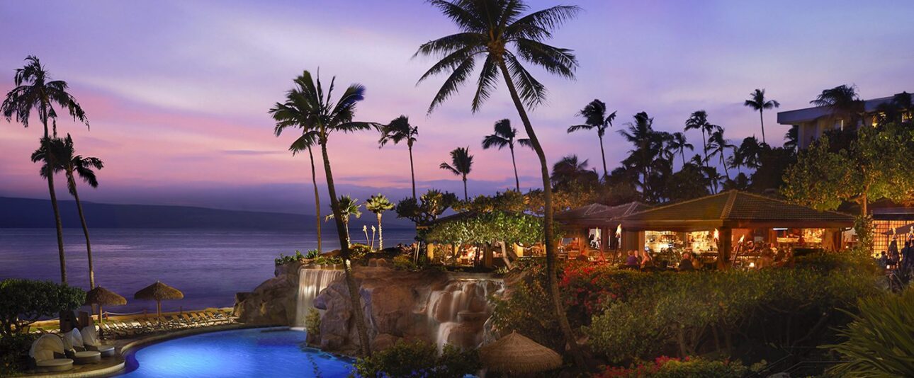 Long view of Hyatt Regency Maui at dusk with palm trees